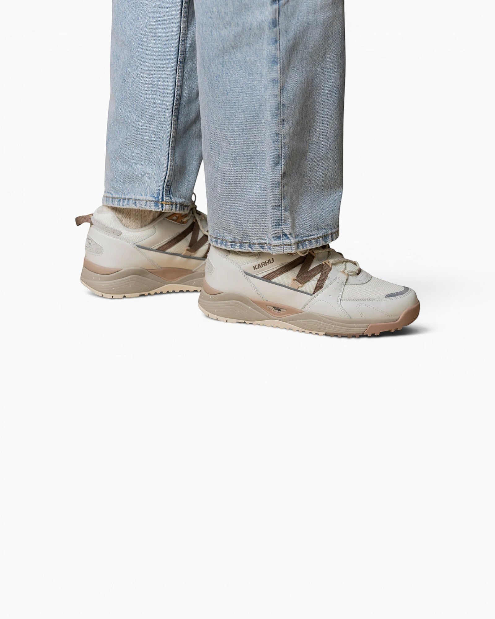 Baskets Karhu Fusion XC blanc cassé et marron portées avec un jean, style outdoor hybride avec semelle technique.